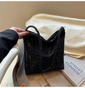Close-up of black tote bag with white polka dots and durable black braided rope handles