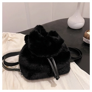 Detail van zwarte faux fur mini rugzak met zachte pluche textuur en leren trekkoorden