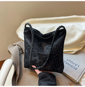 Detail view of black polka dot tote bag with woven handles on a stylish blazer