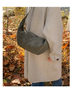 Outdoor shot of large suede crescent bag with white contrast stitching on beige coat
