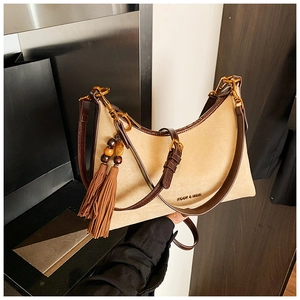 Detailed close-up of beige hobo bag with fringe tassels and wooden bead accents
