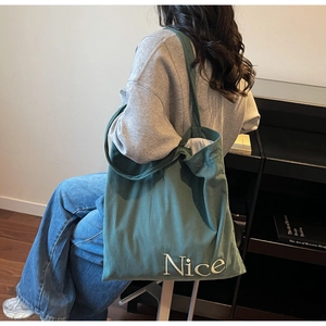 Detail of dark green corduroy tote bag with white Nice embroidery and soft texture