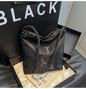 Close-up of black glitter tote bag featuring woven handles and a zipper closure detail