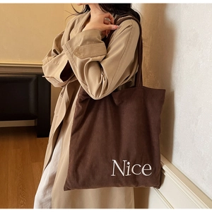 Close-up of deep brown corduroy tote bag showing fine ribbed texture and white Nice text