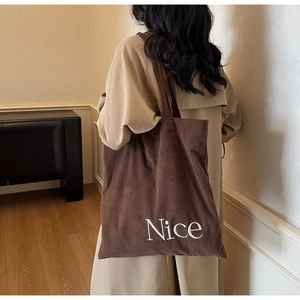 Detail of coffee corduroy tote bag featuring white embroidered Nice letter on the side