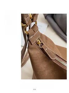 Macro detail of brown tote bag with white contrast stitching and golden zipper