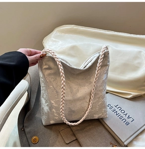 Detail of white sequin tote bag with braided handles and soft textured fabric surface