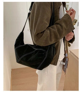 Detail of black suede hobo bag with contrast white stitching on shoulder strap