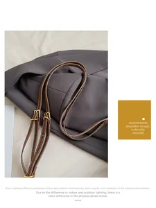 Close-up of brown leather shoulder strap with gold buckle and fine stitching details