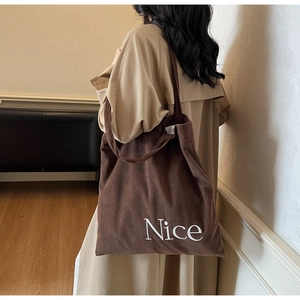 Brown corduroy tote bag showing spacious capacity and nice embroidery on a model