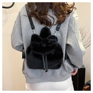 Detail van mini zwarte faux fur rugzak met decoratieve strik en leren riemen