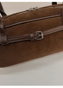 Macro shot of brown frosted suede leather with decorative belt buckle and dual silver zippers