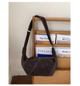 Detail of dark brown suede crescent bag featuring contrast white stitching and metal buckle