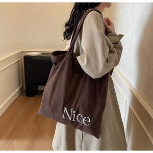 Detail view of large brown corduroy tote bag with Nice lettering for commute