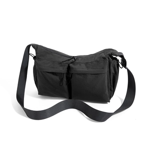 Dettaglio macro della borsa a tracolla nera in nylon con due tasche anteriori a patta