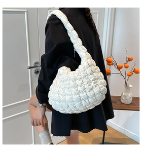 Detalle del bolso de nube acolchado blanco con textura plisada suave en hombro de modelo