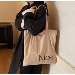 Close-up of beige corduroy tote bag featuring vertical texture and Nice embroidery