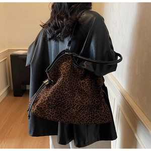 Rear view of a model wearing the large leopard print tote bag with black leather straps