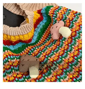 Close-up of rainbow knit bag with 3D crochet mushroom details and wave texture