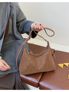 Detail of caramel brown suede tote bag with adjustable strap in warm interior setting