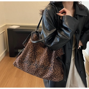 Detail showing oversized leopard print tote bag with black embroidery and leather straps