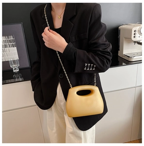 Detalle de bolso amarillo mate con asa recortada y cadena dorada elegante