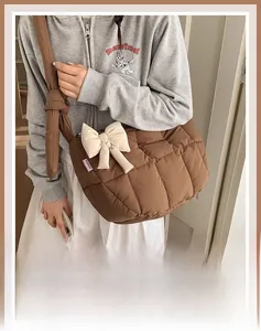Vue latérale d'un grand sac cabas matelassé marron avec un gros nœud crème élégant