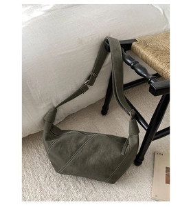 Close-up of hobo bag showing fine dark green leather and white diagonal stitching detail