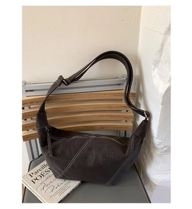 Detail of dark brown suede crescent bag with contrasting white stitching and strap
