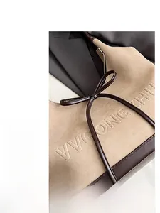 Detail of beige suede tote bag featuring debossed VVGONGZHIHU logo and leather bow