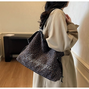 Close-up of leopard print tote bag with black leather strap and cursive lettering detail