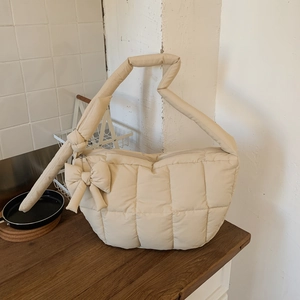 Détail du sac cabas beige matelassé avec bandoulière rembourrée et nœud décoratif