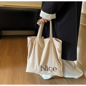Close-up of beige corduroy tote bag with Nice letter embroidery and textured fabric