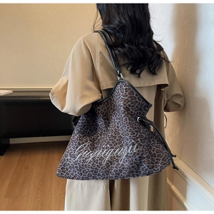 Detail of leopard print tote bag with black leather straps and white letter embroidery