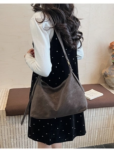 Detail of dark brown leather hobo bag with contrast stitching shown on model shoulder