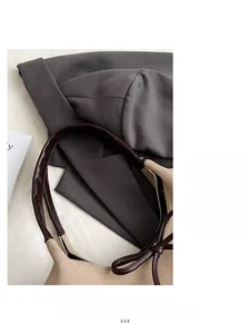 Detailed close-up of bow knot strap on beige faux suede tote over a grey blazer