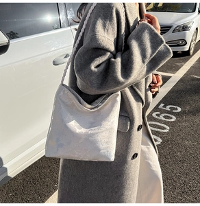 Close-up of a white shoulder bag featuring woven straps and subtle iridescent texture