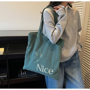 Detail showing dark green corduroy tote bag with Nice print in a casual lifestyle setting
