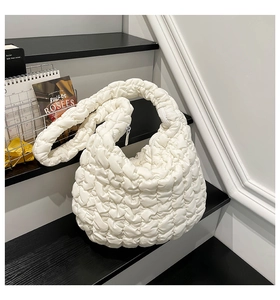 Detail der weißen gesteppten Cloud-Tasche mit Textur auf schwarzen Holzstufen