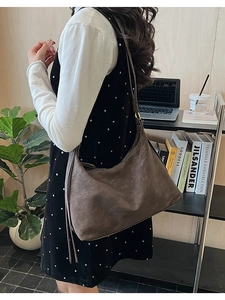 Model wearing a dark brown vintage suede tote bag with fringe detail in a cozy office