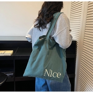 Close-up of dark green corduroy tote bag featuring 'Nice' letter embroidery texture