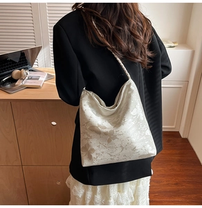 Detailed close-up of white butterfly print tote bag with woven shoulder strap on a model