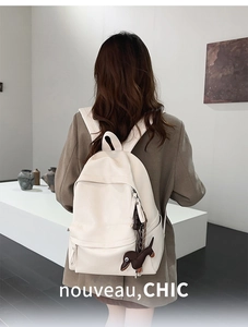 Détail d'un sac à dos en cuir PU blanc crème avec un joli porte-clés de chiot teckel brun