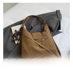 Detailed shot of brown matte leather hobo bag with cross strap buckle and dog charm