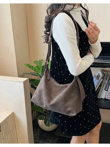 Detail of dark taupe hobo bag showing brushed texture and white decorative stitching