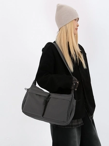 Grande borsa a tracolla grigio scuro con due tasche indossata da una modella