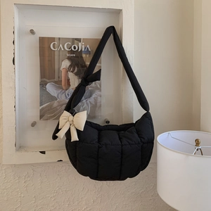 Détail du sac bandoulière noir matelassé avec nœud crème et texture rembourrée
