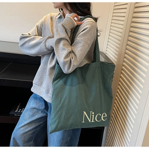 Detail of green corduroy tote bag showing 'Nice' embroidery and soft fabric texture