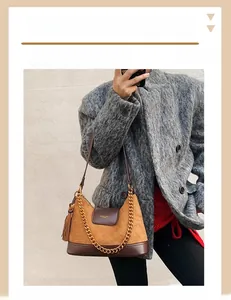 Détail du sac seau matelassé en daim marron avec chaîne dorée et pompon décoratif