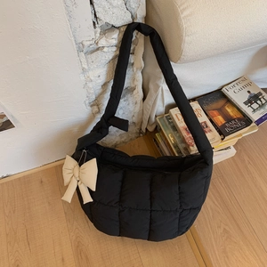 Détail d'un sac à bandoulière matelassé noir avec un grand nœud écru et texture souple